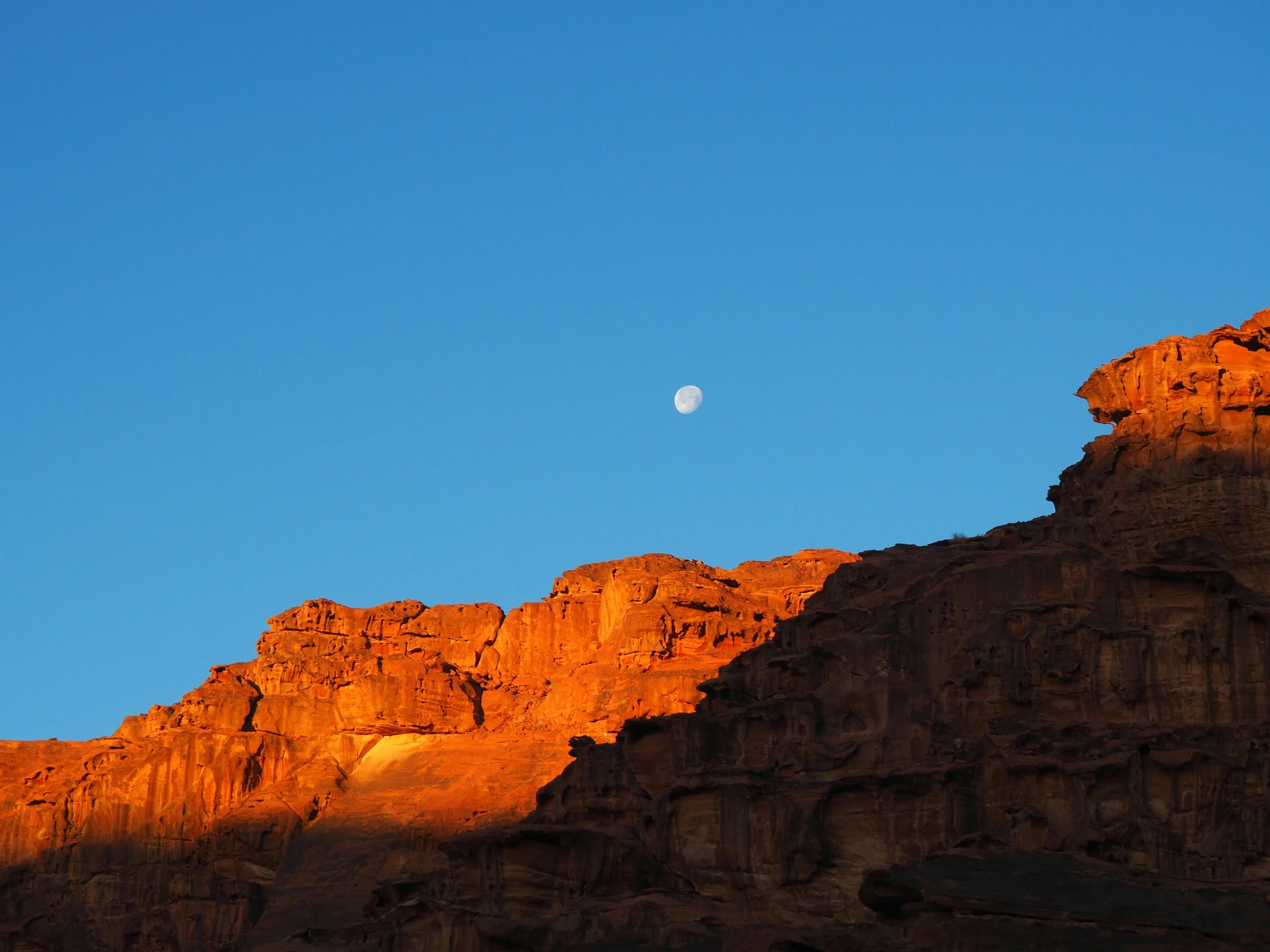 the sun is setting in the mountains behind a mountain top