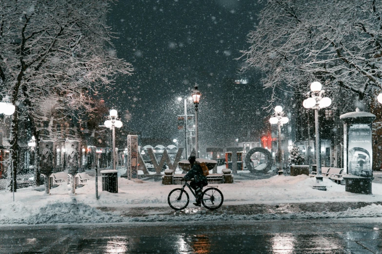 a snowy city at night on a dark street with trees and lamps