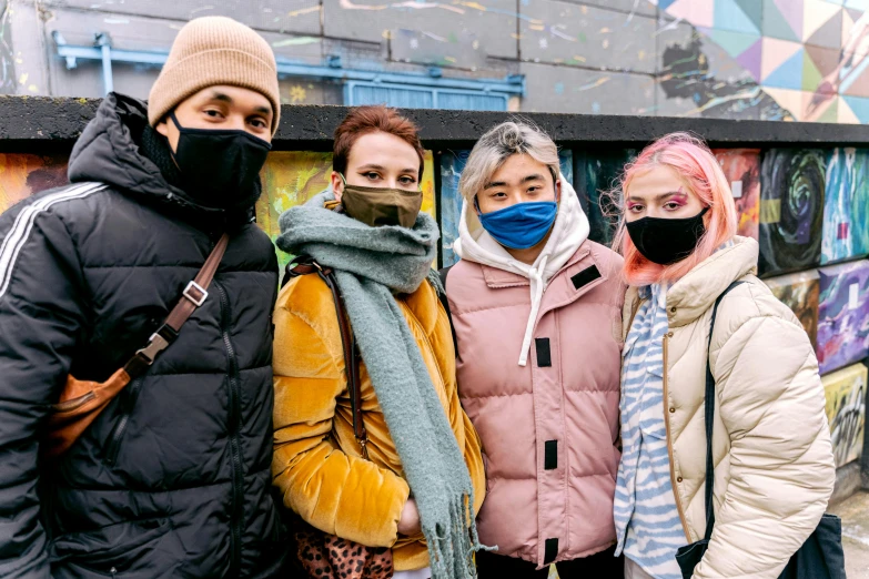 five people wearing masks standing in front of graffiti