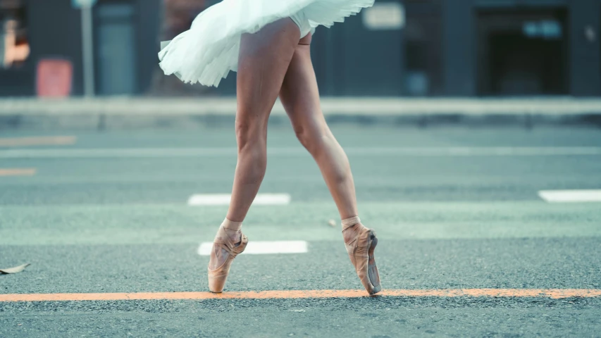 there is a woman with ballet shoes walking down the street