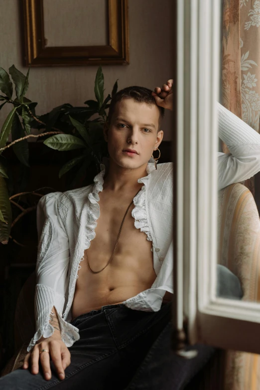 a man in white shirt sitting next to window