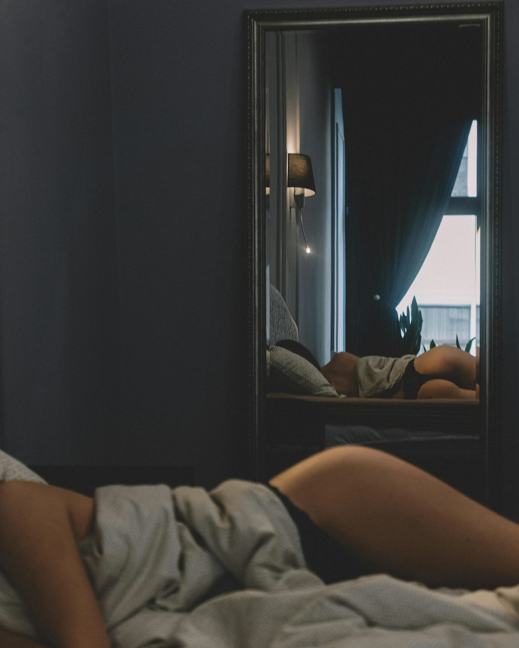 a person laying in bed under a large mirror