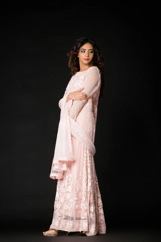 a woman is wearing a pink colored indian outfit