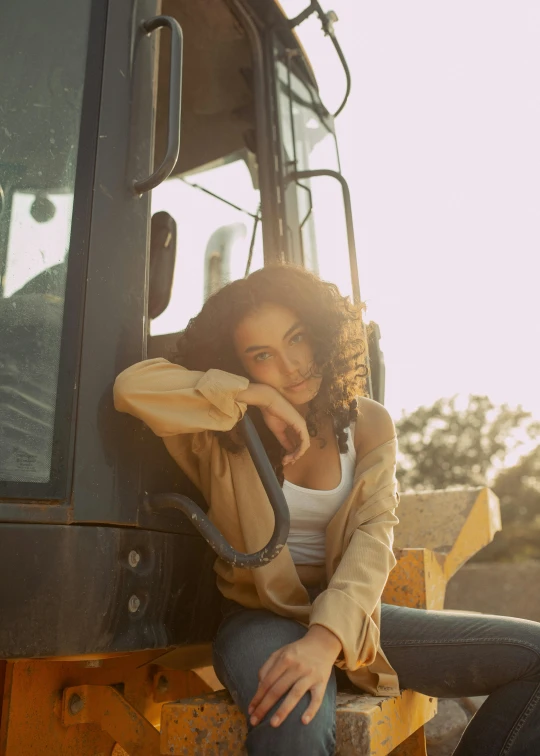 woman in a yellow jacket sitting on a large black forklift