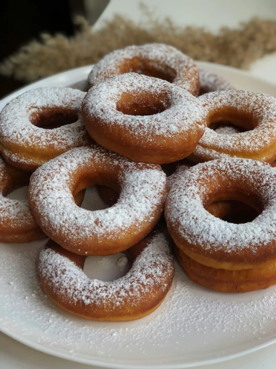 some sugared doughnuts are sitting on a white plate