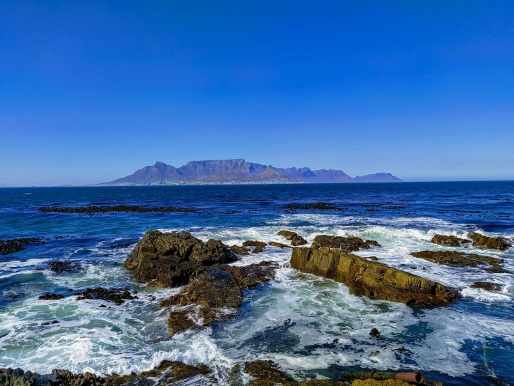 a rocky beach on an ocean with blue skies