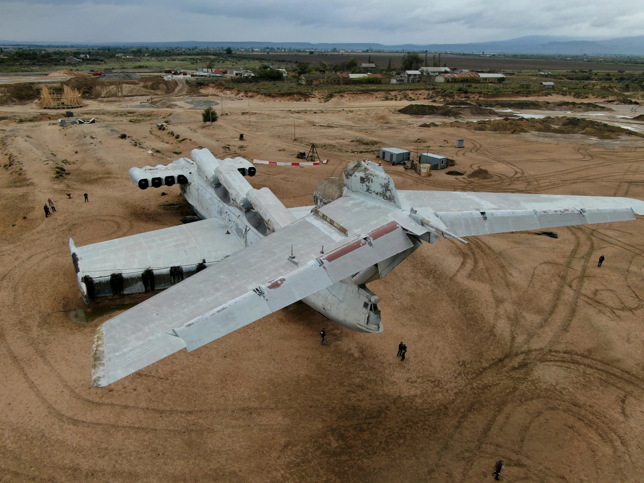 a large silver plane in a field with many other planes in the background