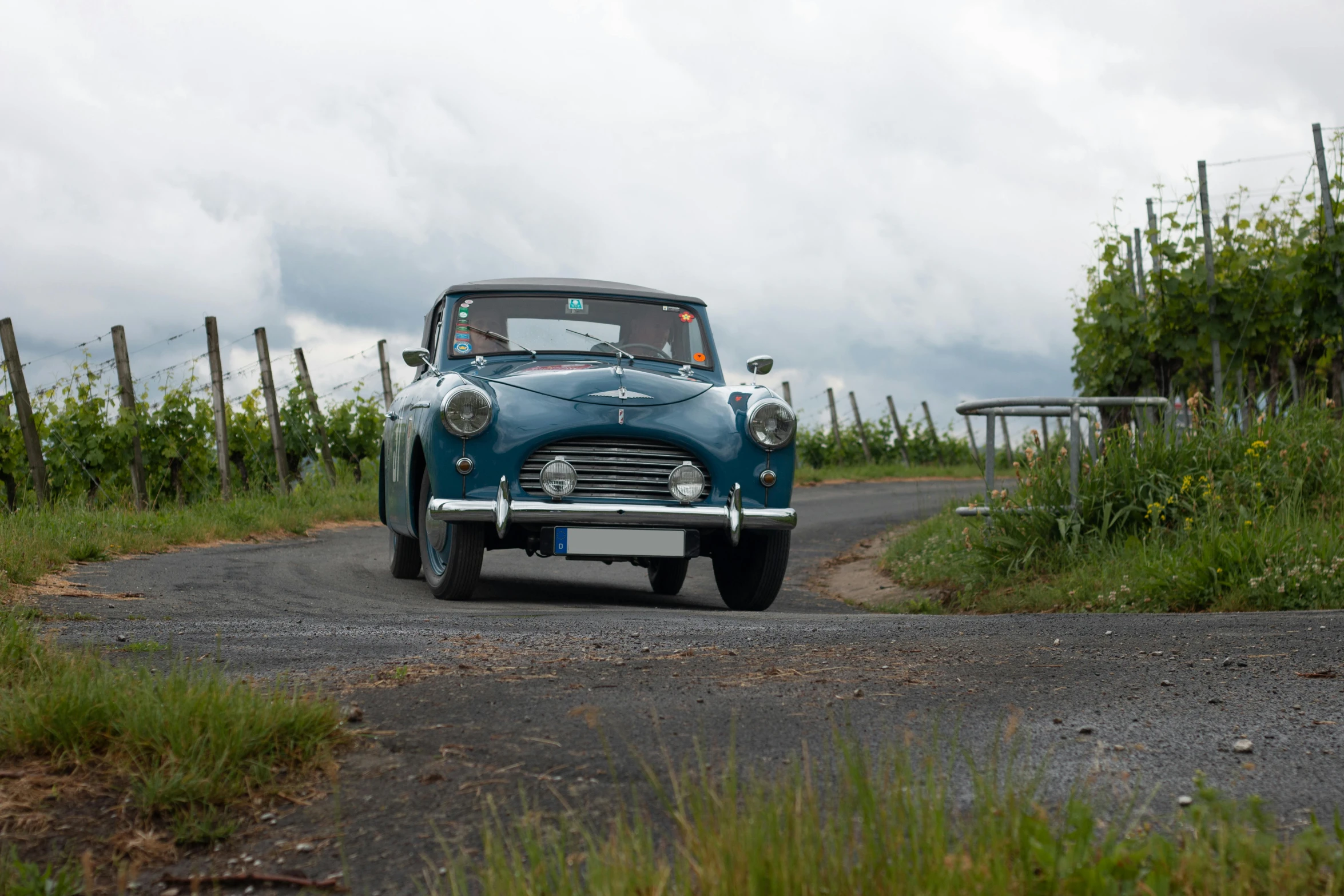 an old blue classic car driving on the street