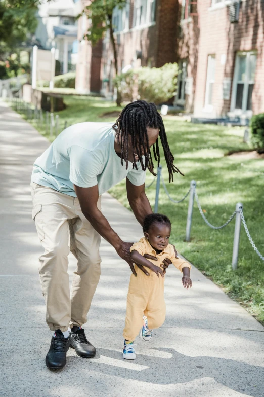 a child is hing his dad's hand while walking down the street