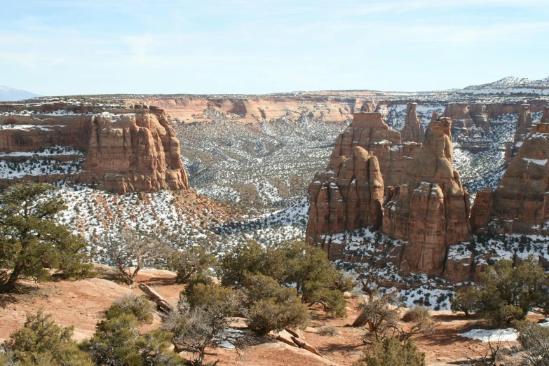 a view of rocky terrain and the surrounding mountains with snow