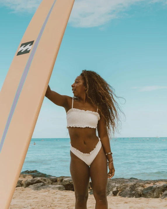 a black woman wearing a white bikini holding a surf board
