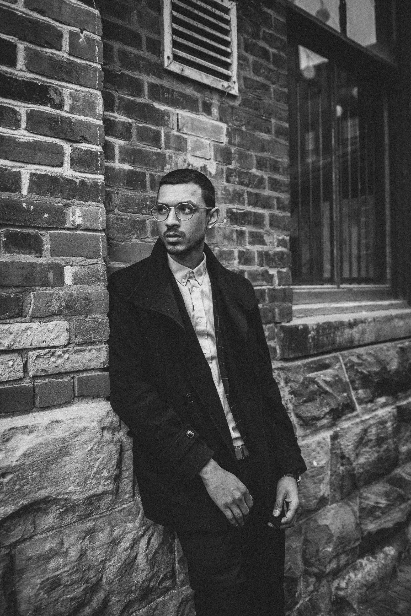 a man standing next to a building and a brick wall