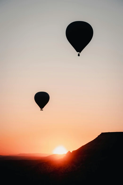 the sun rises with the horizon filled with  air balloons