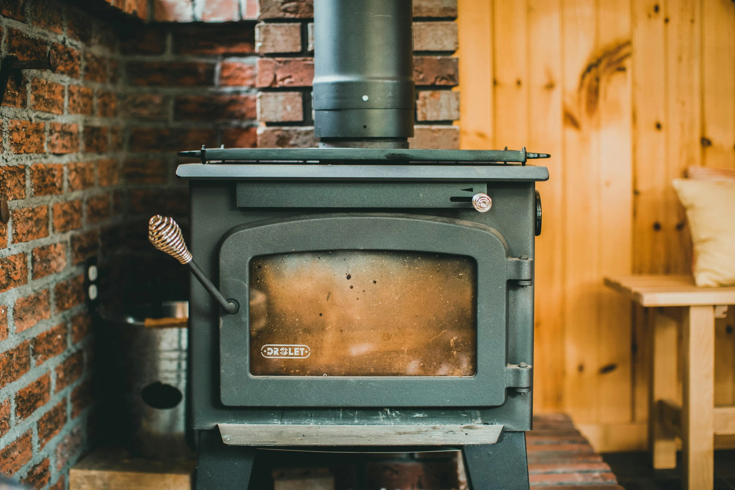an old fashioned wood stove sits in front of a brick wall