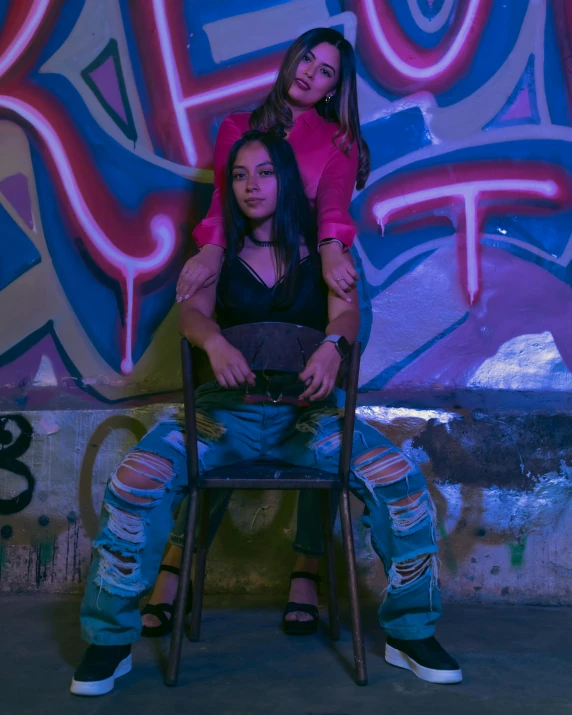 a girl sitting on a chair next to a lady