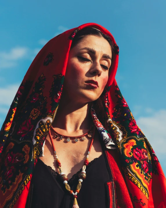 a woman with red shawl wearing a beaded necklace