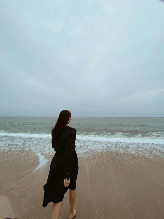 a person is standing on the beach flying a kite