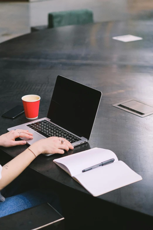 a woman sitting on the desk working on her laptop