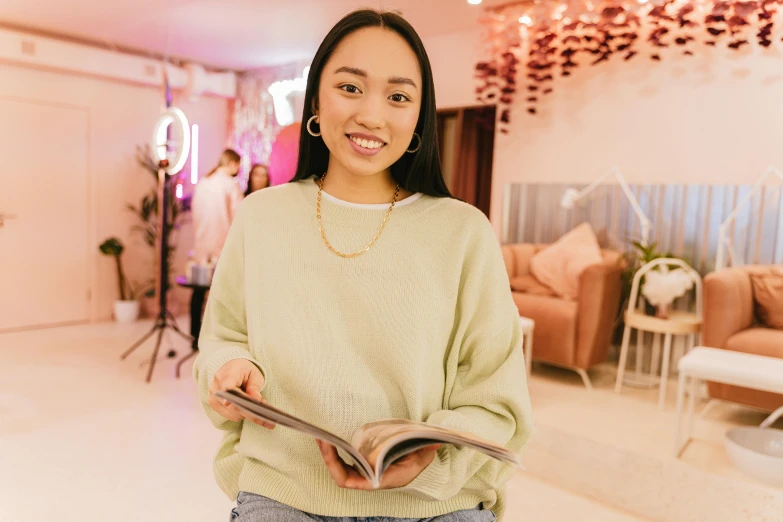 woman in green sweater holding open book and standing