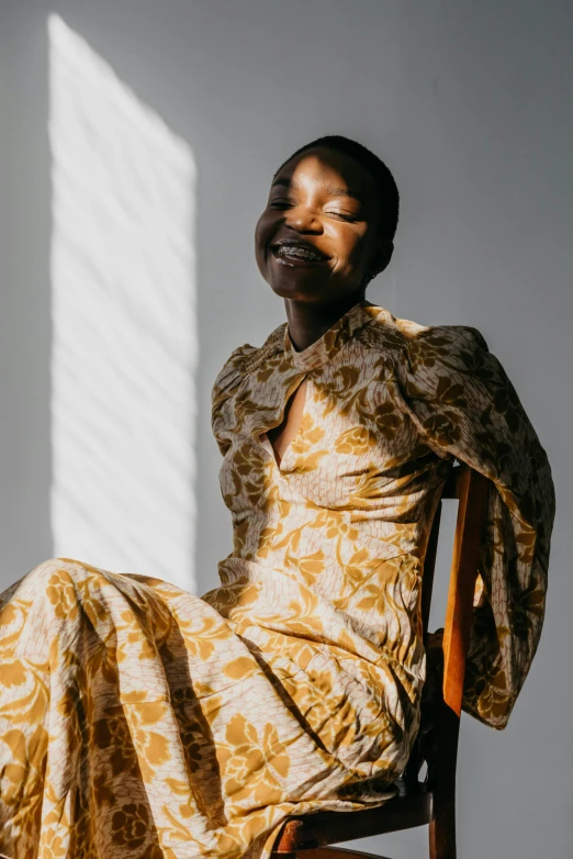 woman in printed dress sitting down with her hands on her hips