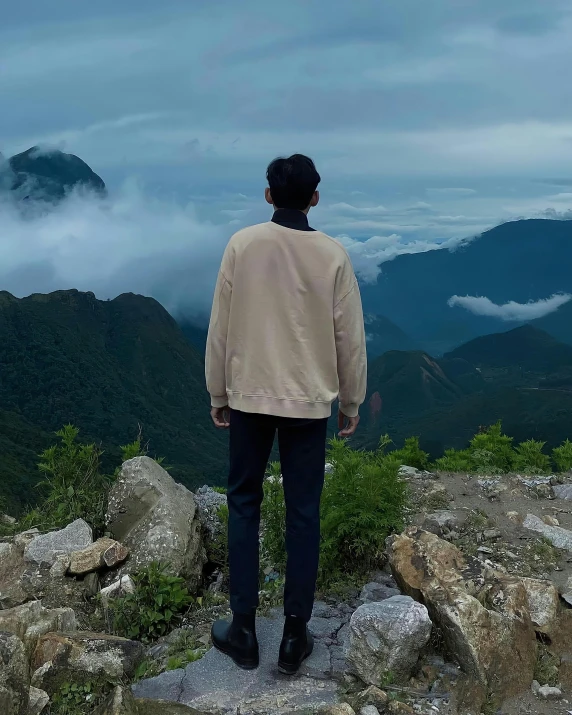 man standing on rock in mountains watching clouds from top of mountain