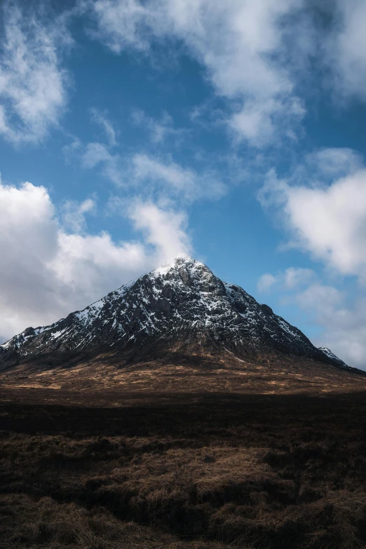 the snowy mountains range over a field on a cloudy day