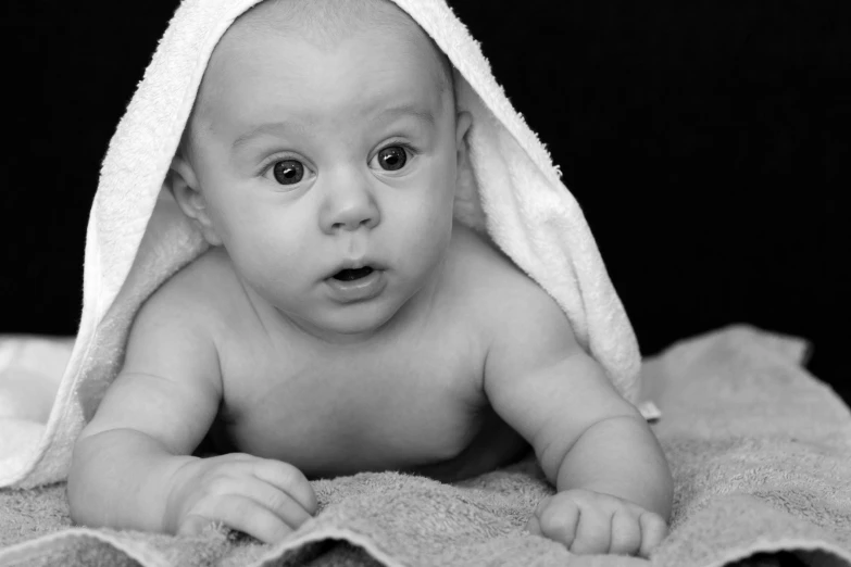 a baby laying down in front of a white blanket