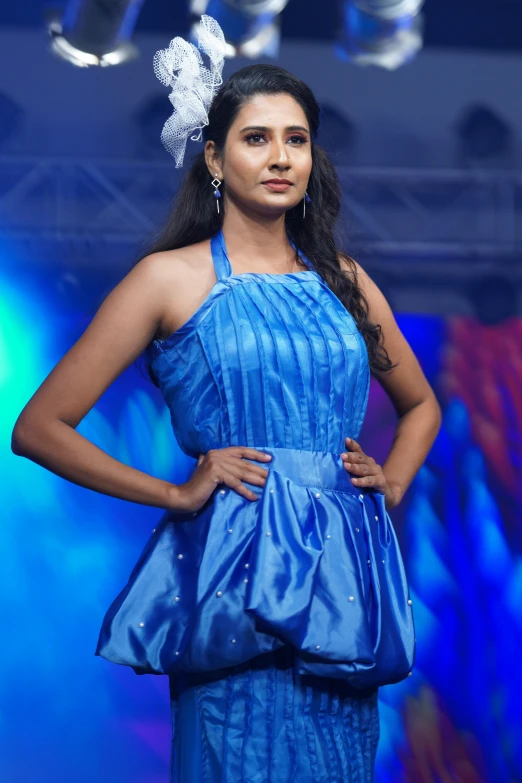 a model in a blue dress poses for the camera