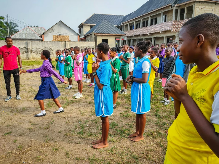 children in uniforms practicing soccer with other adults