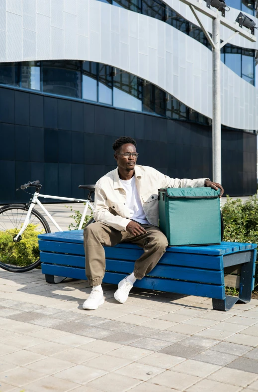 a man sitting on a blue bench holding a suitcase