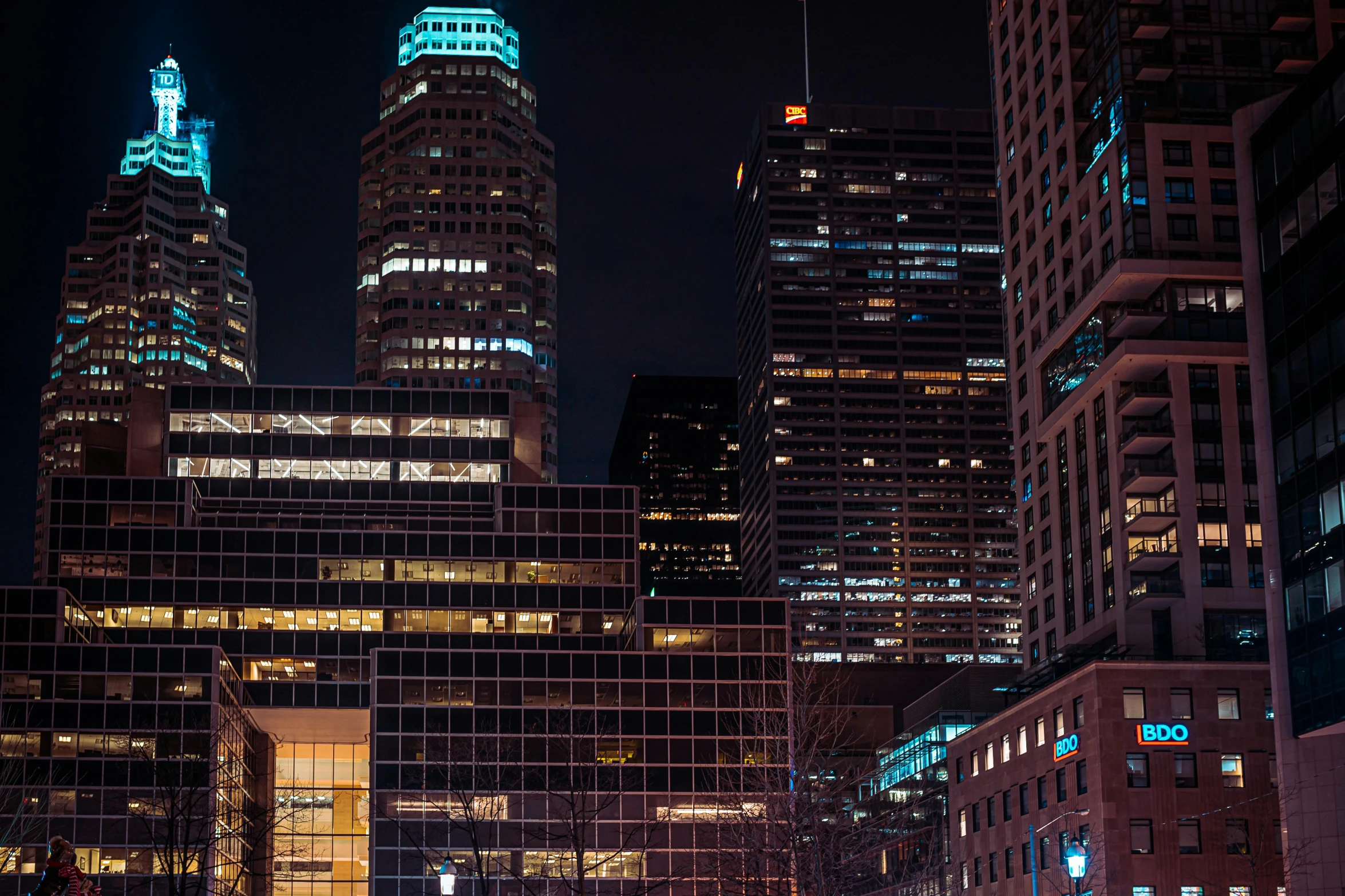 cityscape at night with a green tower lit up in blue