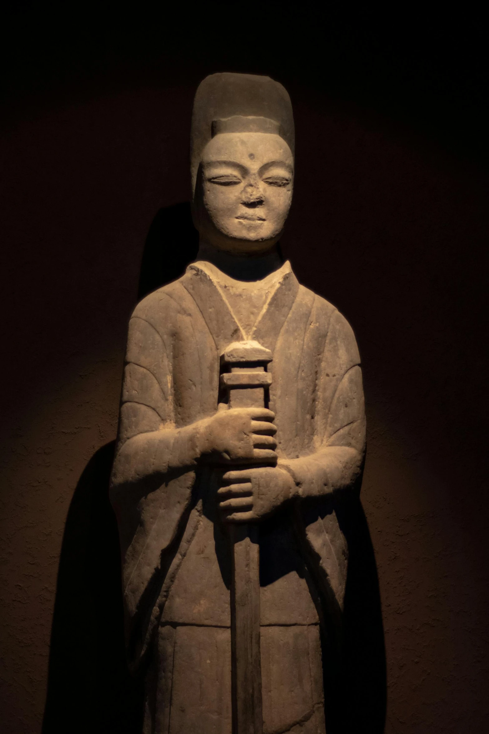 a statue of a person holding a small pole