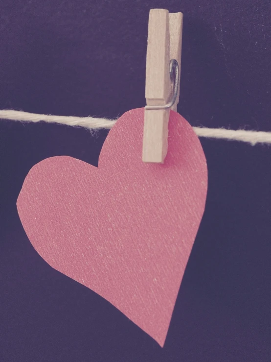 a pink heart attached to clothes pins