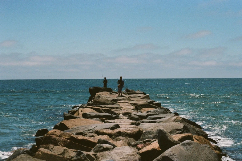 two people are standing at the end of a stone pier