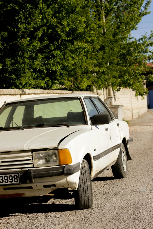 an old car sits in the middle of a paved driveway