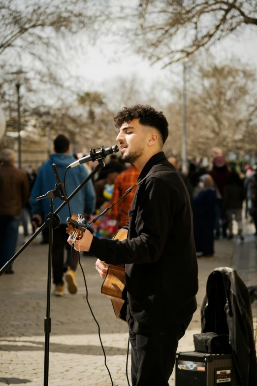 the man stands in front of a microphone, while playing his instrument