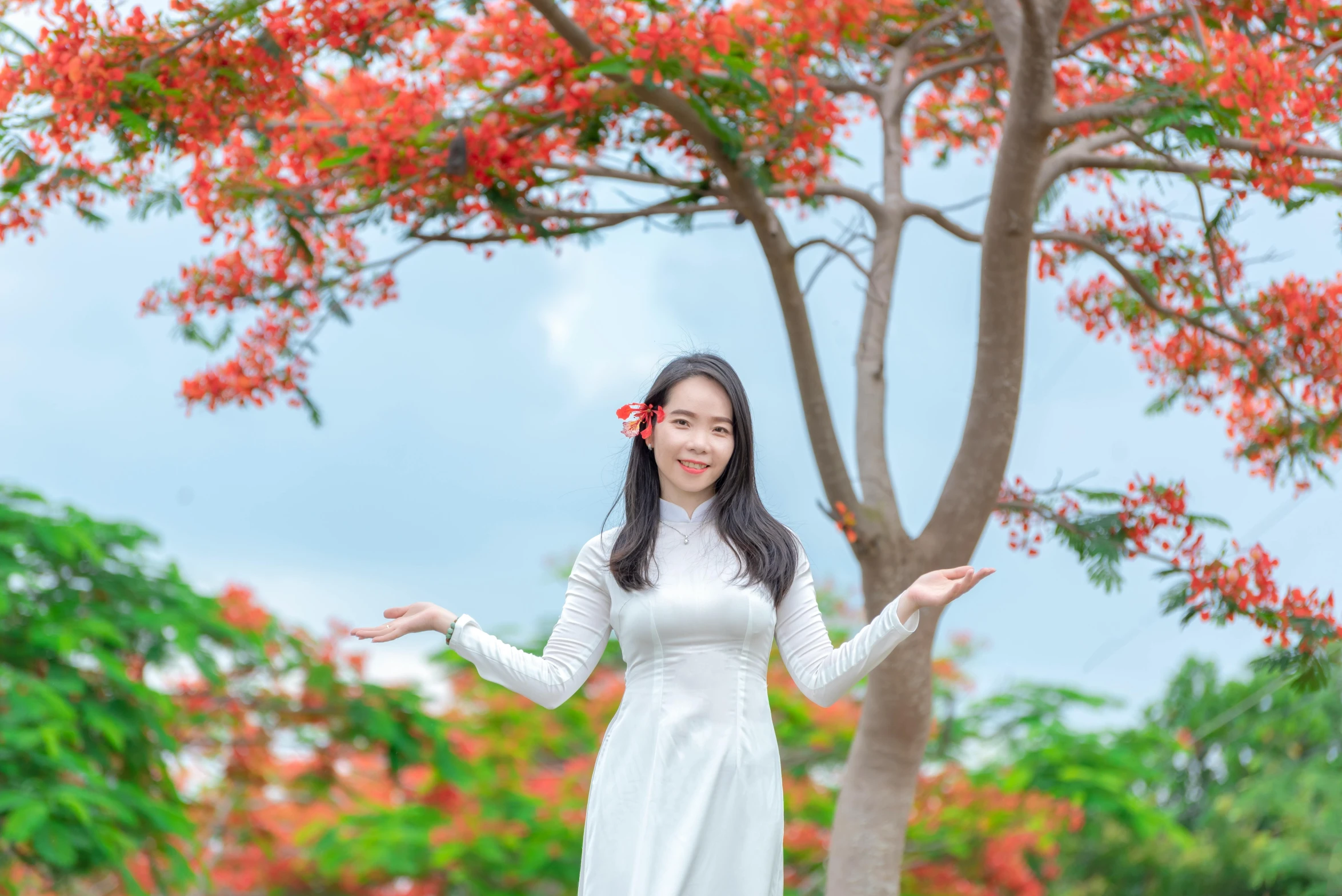 a girl poses with a tree and bushes in the background