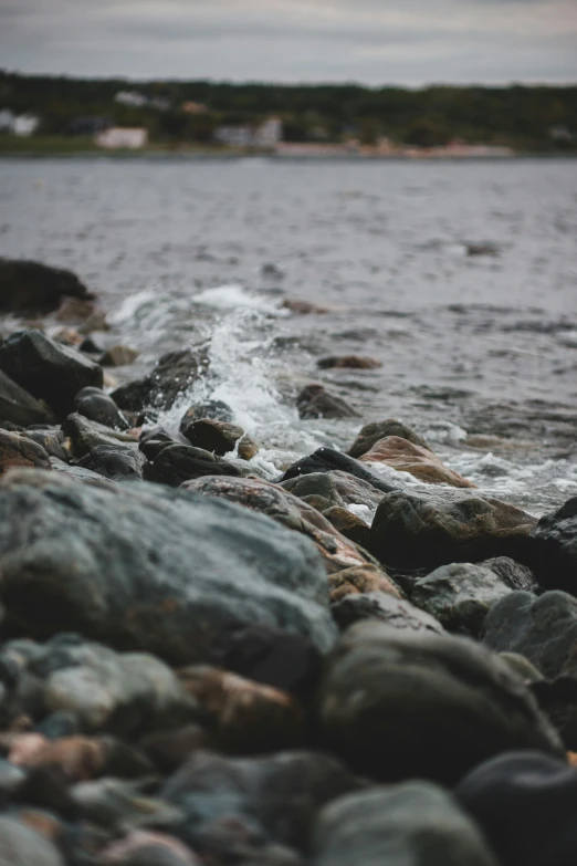 rocks near water and buildings in the distance