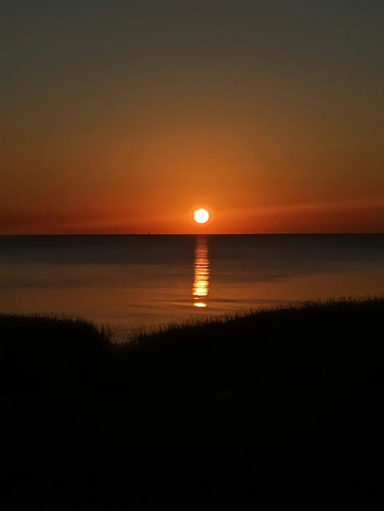 a boat that is floating in the water at sunset