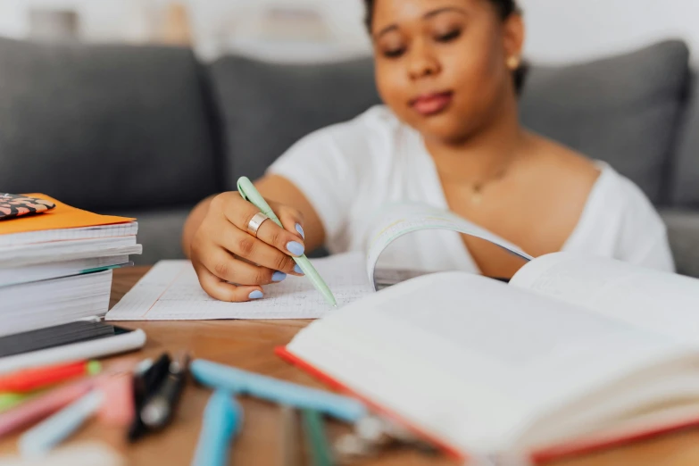 a woman in white shirt writing on top of a table