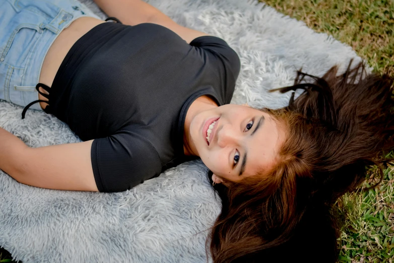 a girl laying down on a fluffy rug smiling