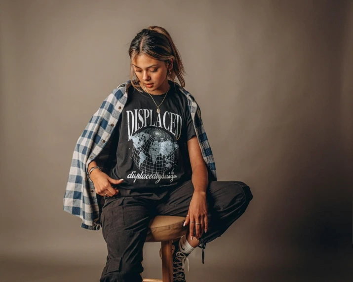 a girl with dreadlocks sitting on a stool