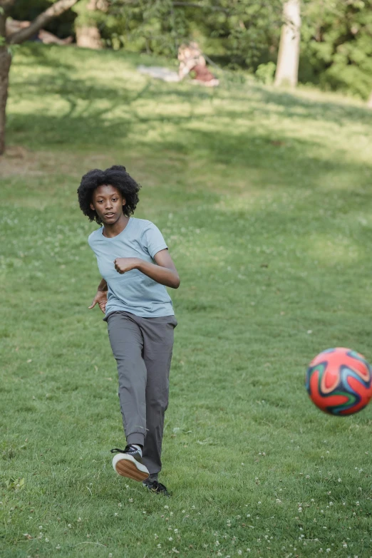 a woman playing soccer on grass in a park