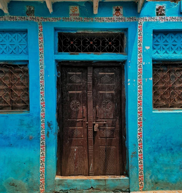 an ornately decorated door in front of a blue building