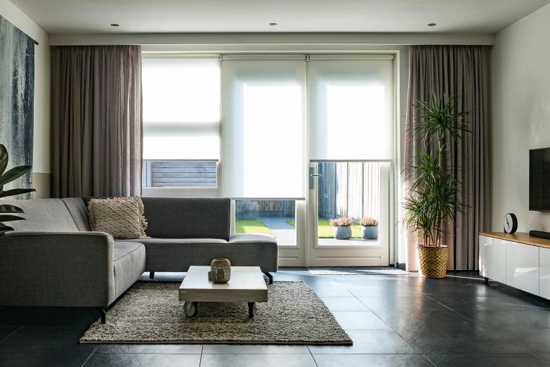 a living room with a large gray couch next to an open window