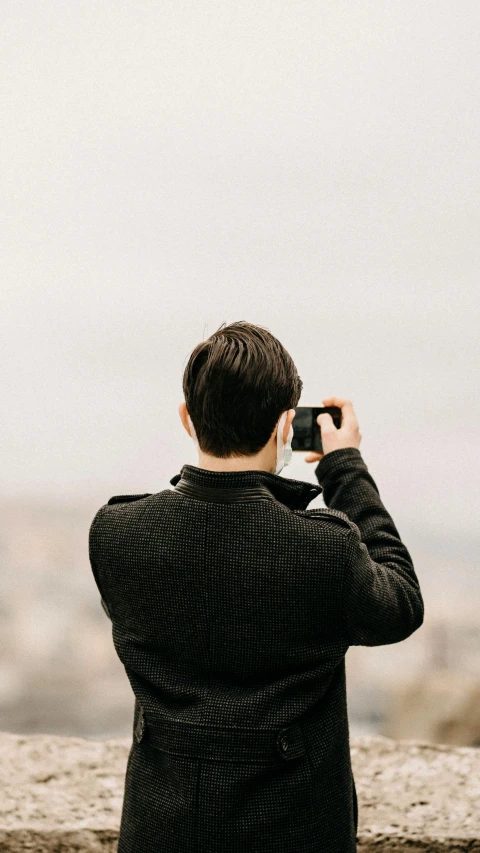 a man looking out on the ocean while holding a phone