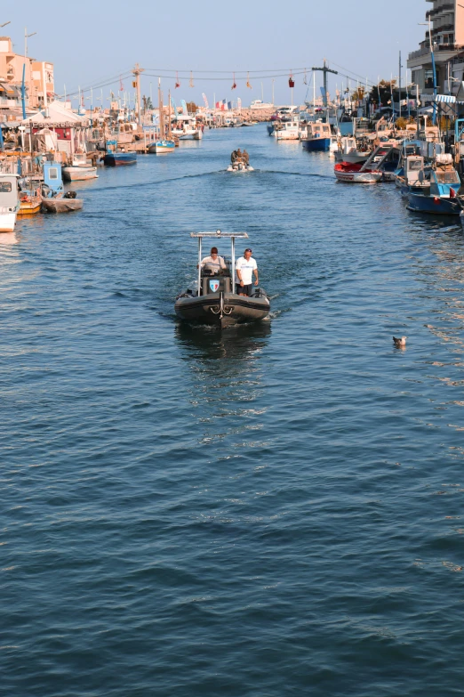 three people are riding a boat in a crowded canal