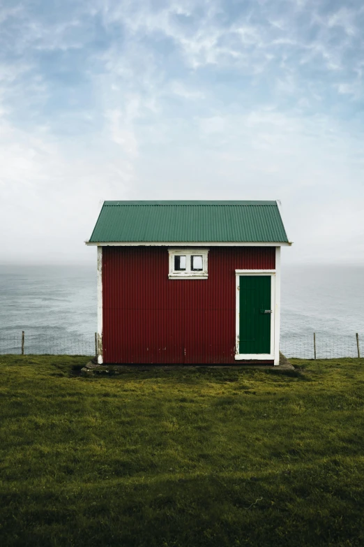 a red building sitting on top of grass by the ocean