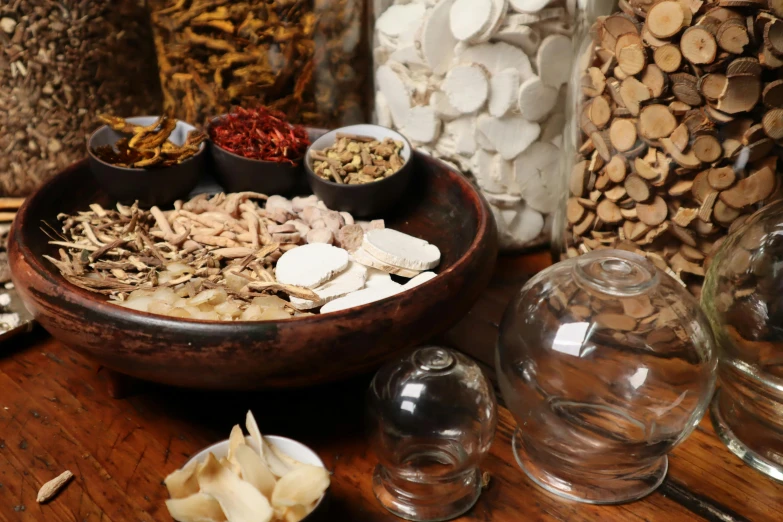 various spices in small bowls and spoons sit next to some large glass jars