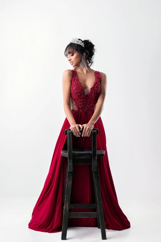 a woman with dark hair wearing a red dress sitting on top of a chair